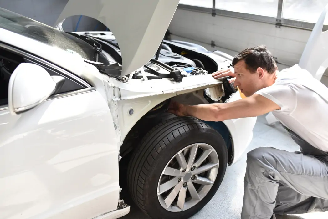 Technician inspecting collision damage on a vehicle